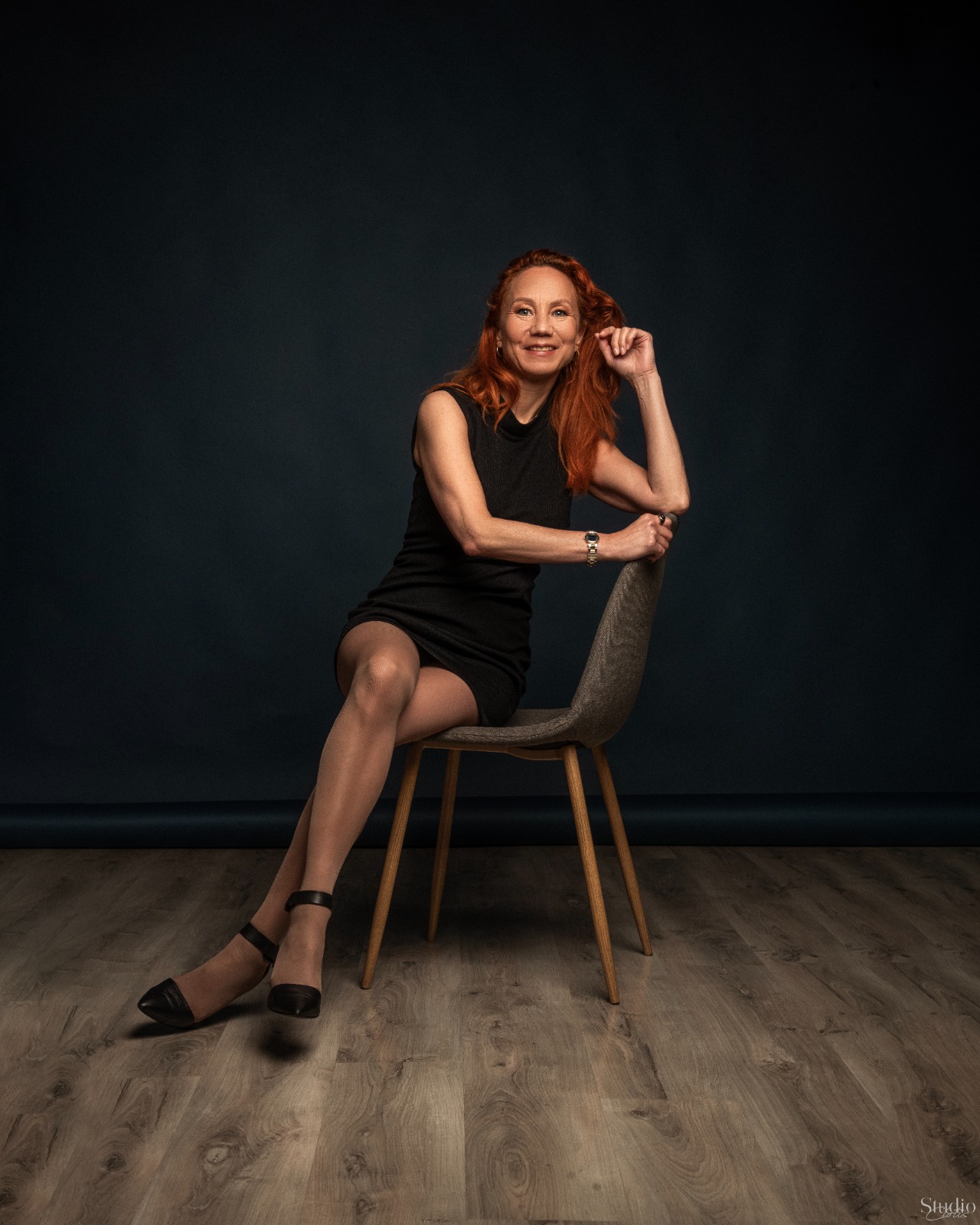 Olga Petrova souriante, assise sur une chaise
